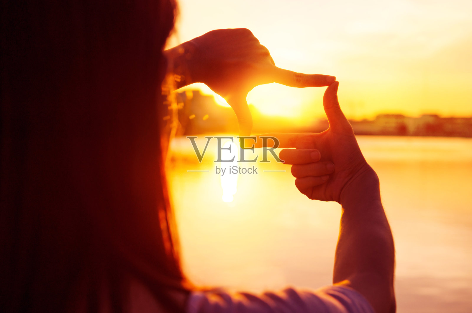 女人的双手在夕阳下做着手势。照片摄影图片