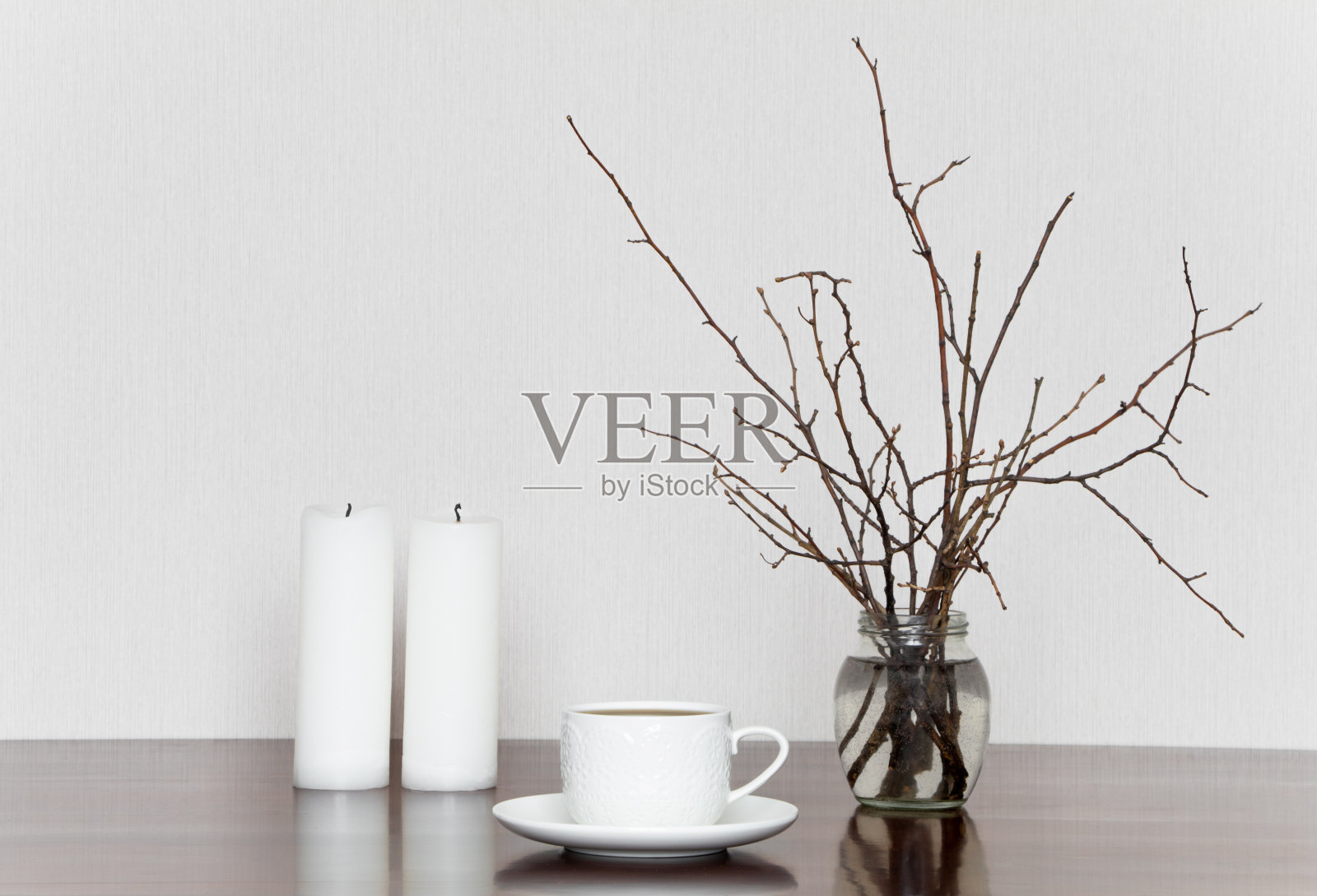杯子，蜡烛和瓶子里的树枝。灰白色静物照片摄影图片