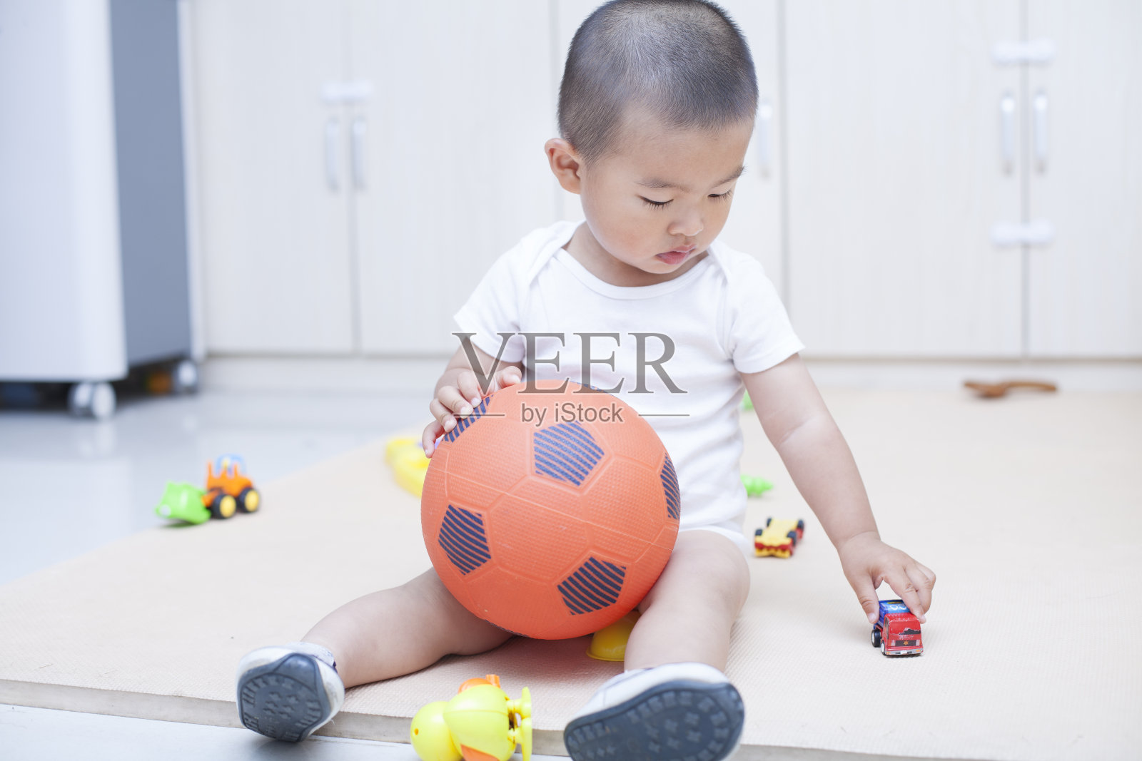 可爱的中国小男孩在室内踢足球照片摄影图片