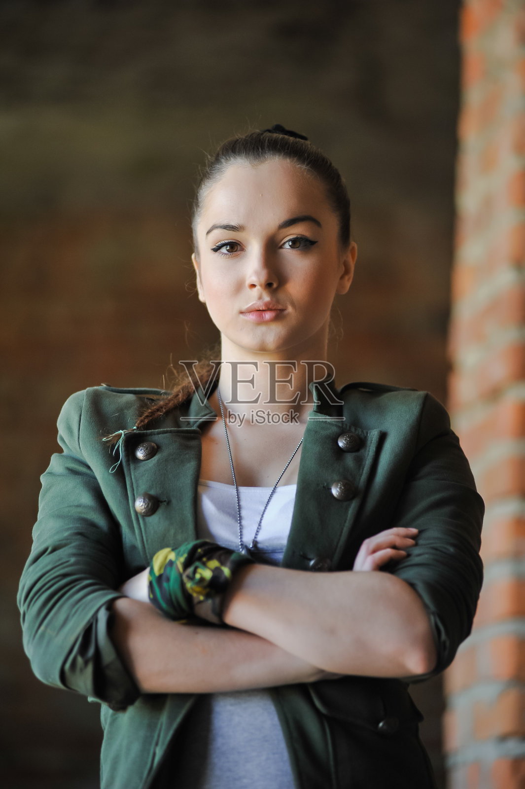 在砖墙附近的女孩在军事风格。照片摄影图片