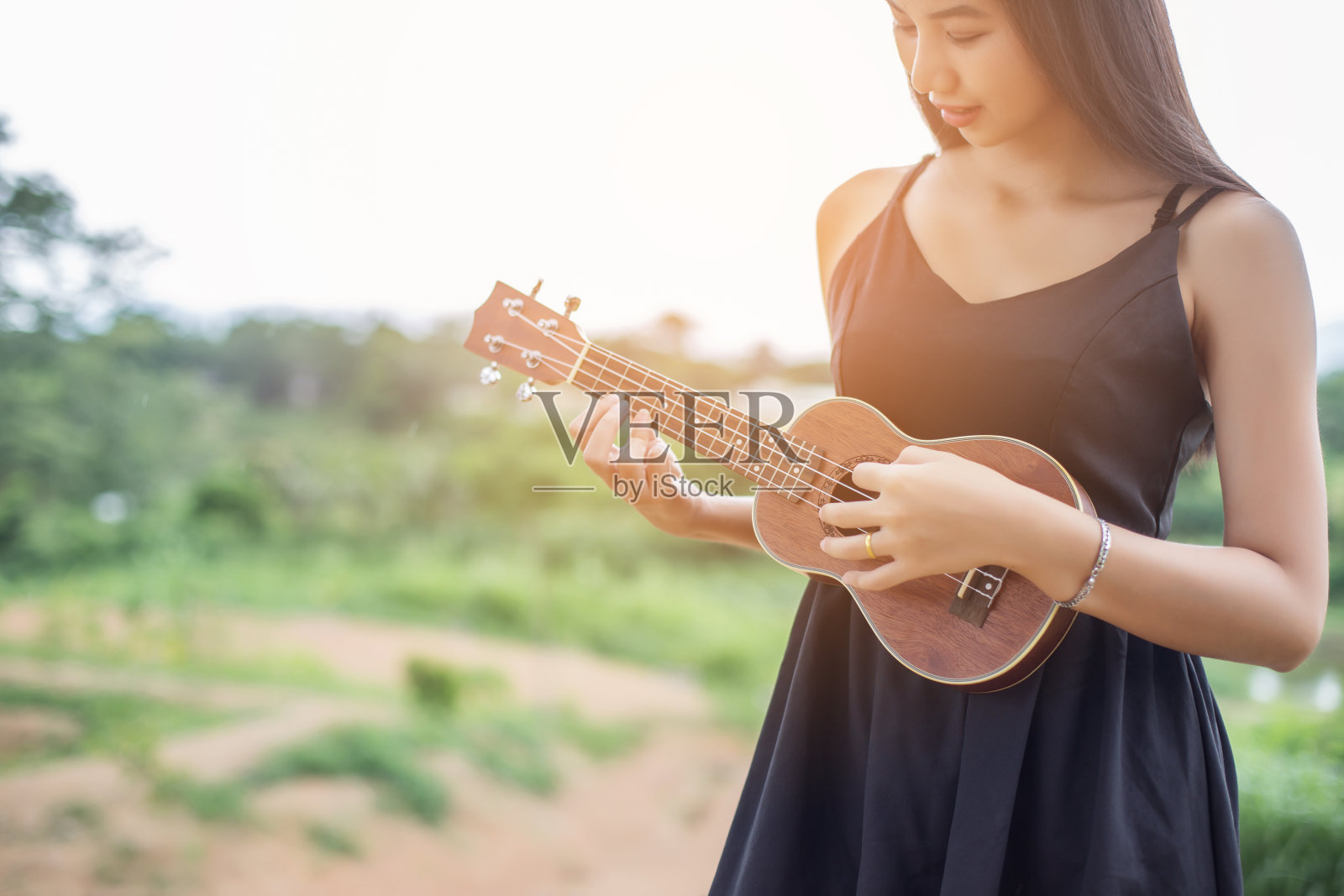 美女肩上扛着吉他，大自然公园外的夏天。照片摄影图片