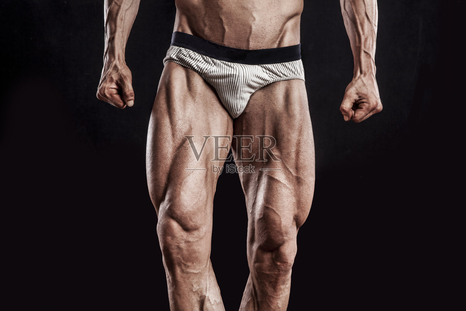 肌肉男子的腿在黑色的背景，健美运动员照片摄影图片