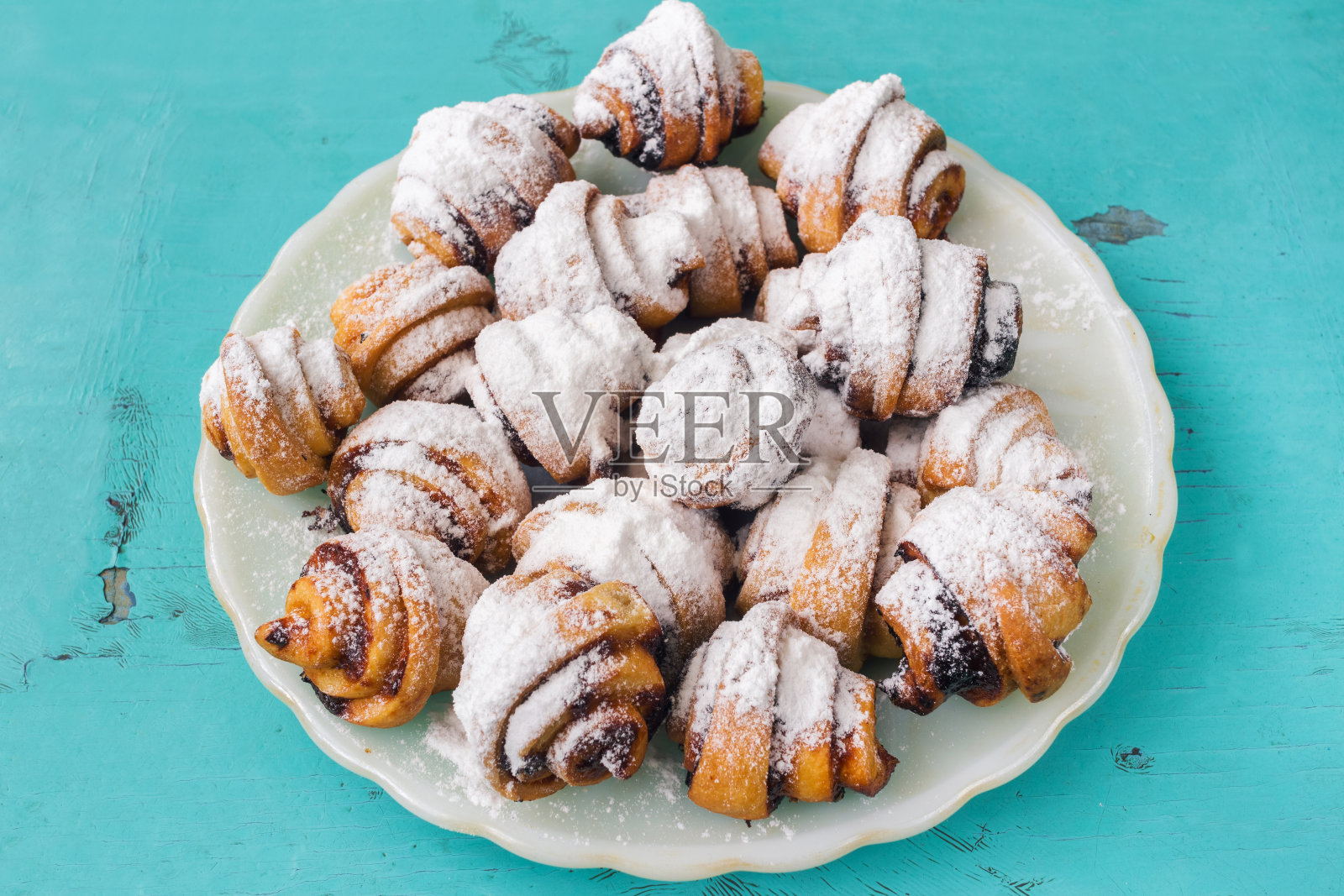 自制的小甜饼撒上糖粉，放在白色盘子里，木质的蓝色背景上。照片摄影图片