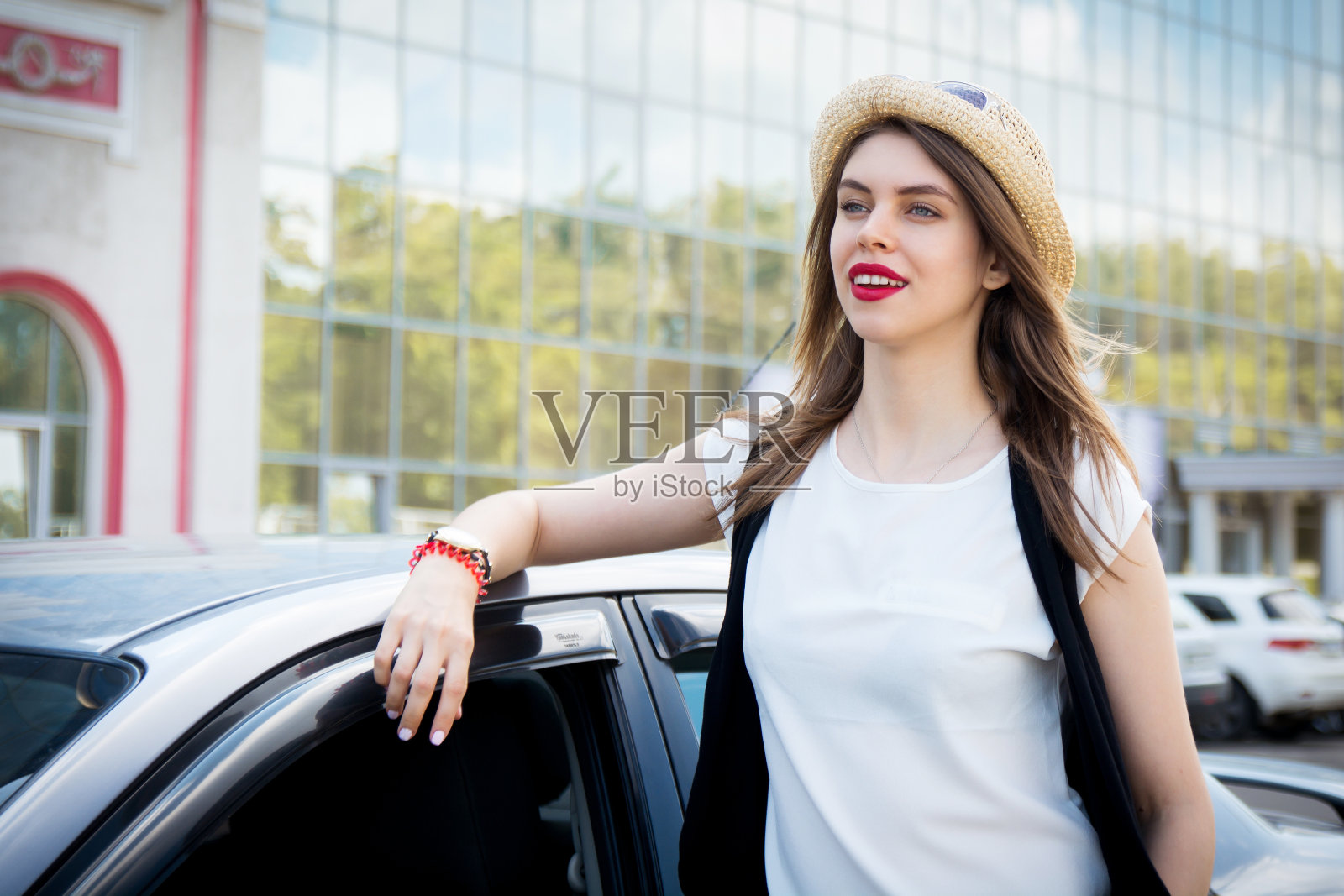 漂亮的时髦女孩站在她的车旁边照片摄影图片