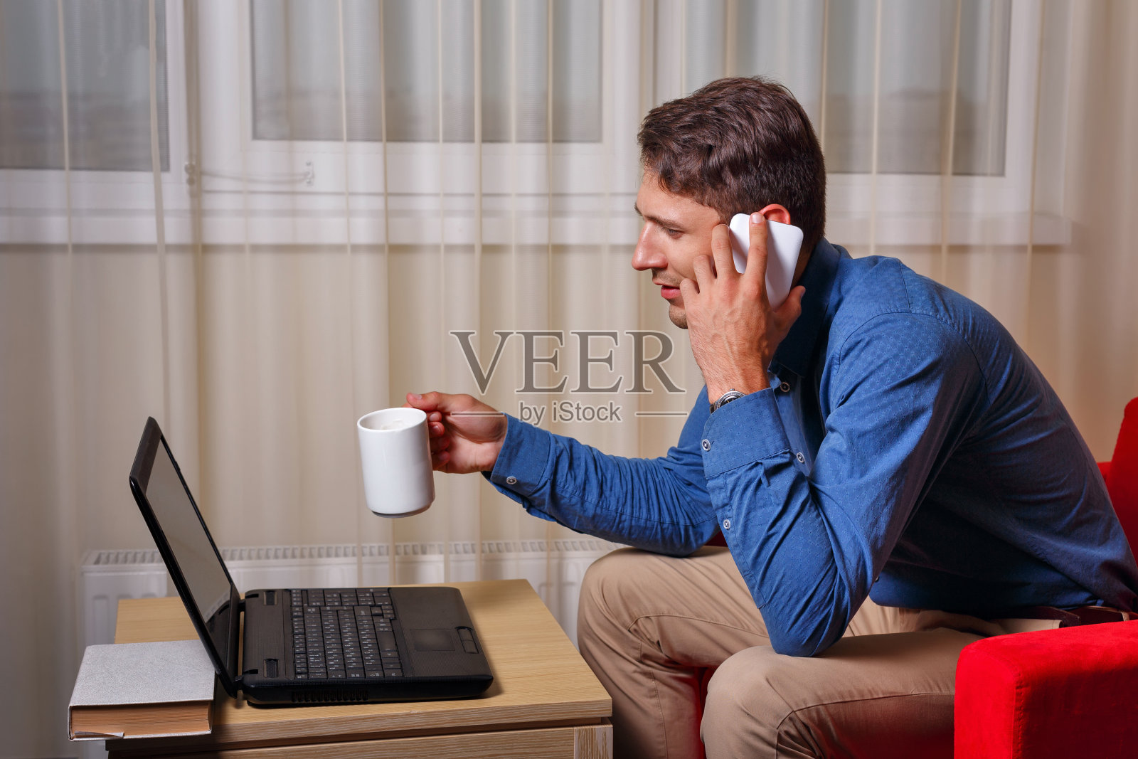 男人一边用笔记本电脑工作一边打电话照片摄影图片