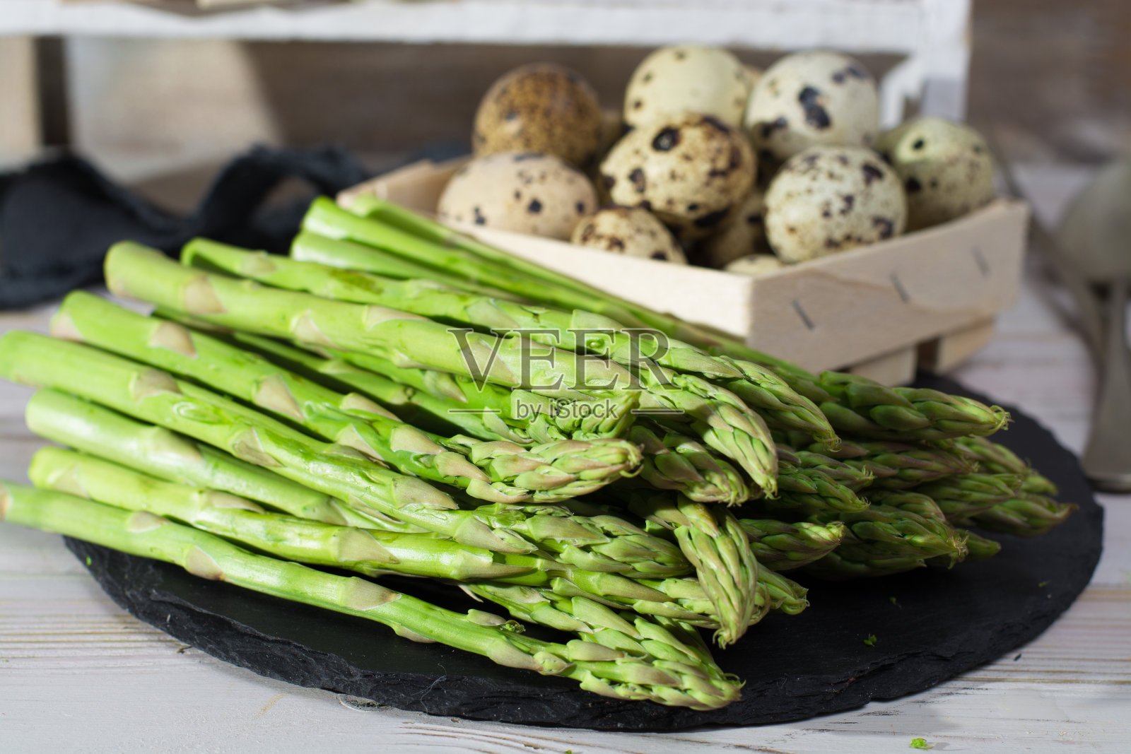 春季-新鲜的绿芦笋和鹌鹑蛋放在黑色的石板上照片摄影图片