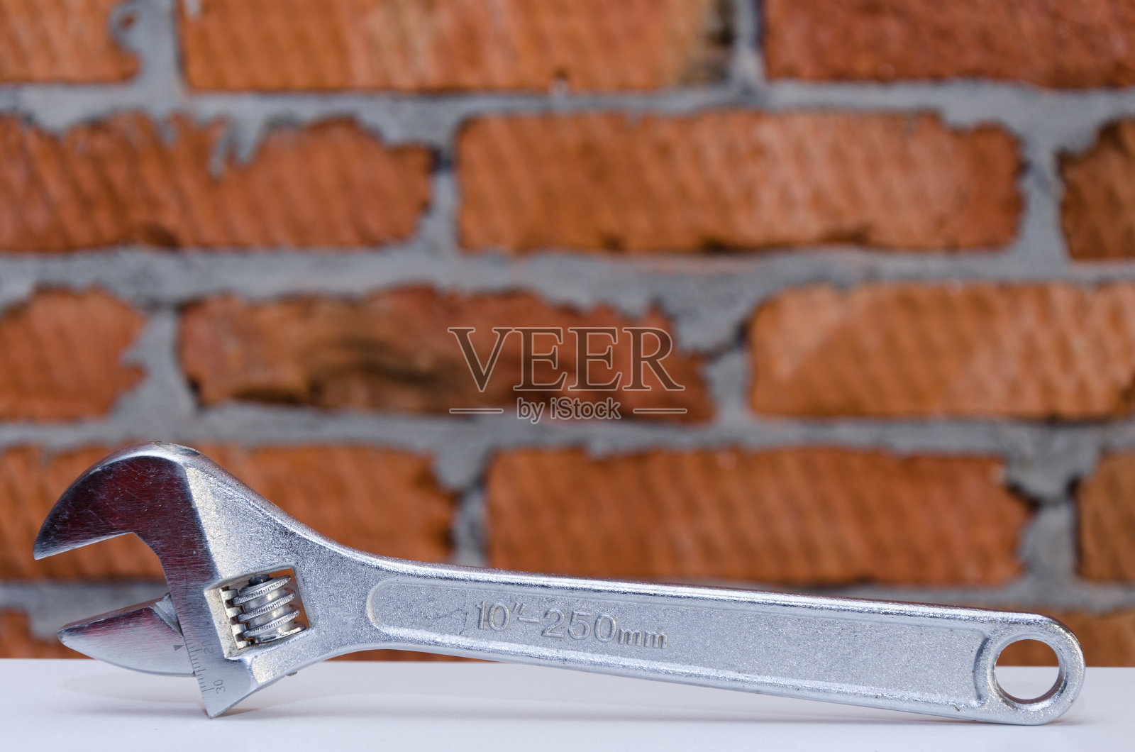 活动扳手隔离在砖墙背景上照片摄影图片