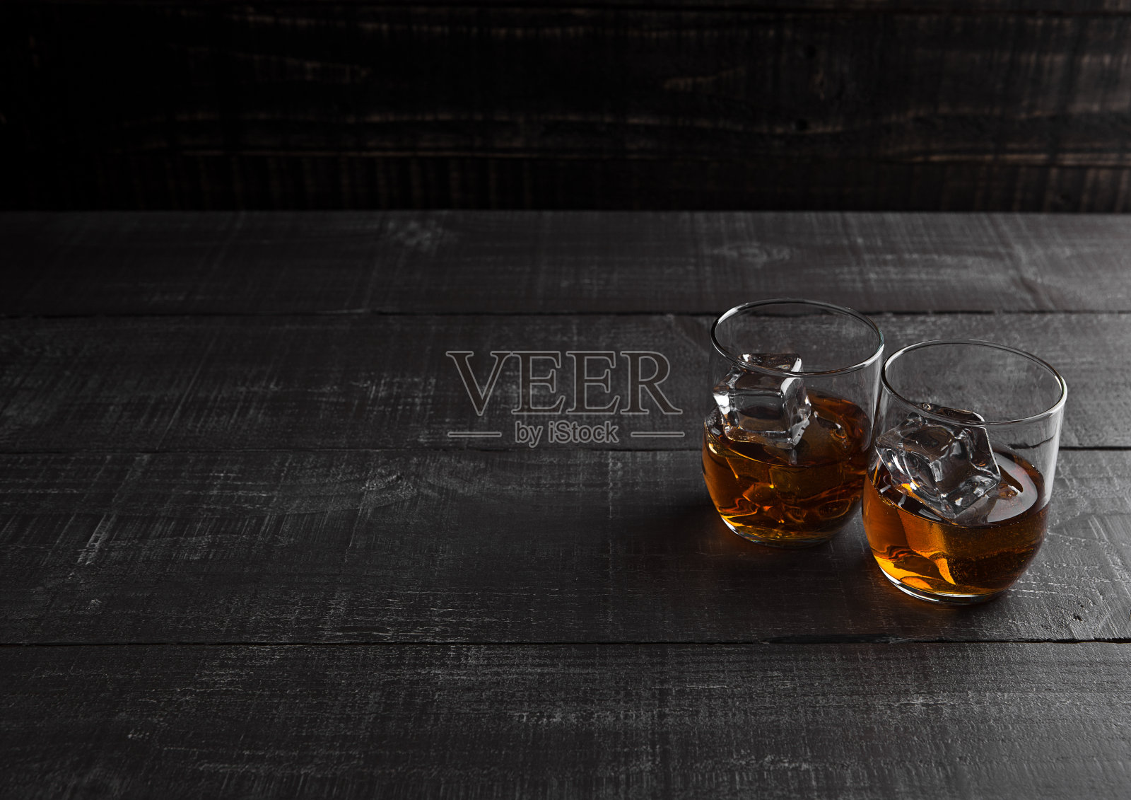 玻璃杯的威士忌与冰的木制背景照片摄影图片