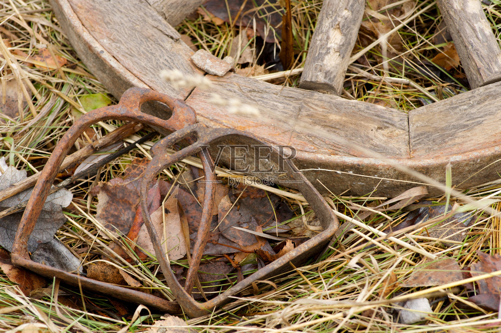 生锈的马镫躺在一个木轮旁边照片摄影图片