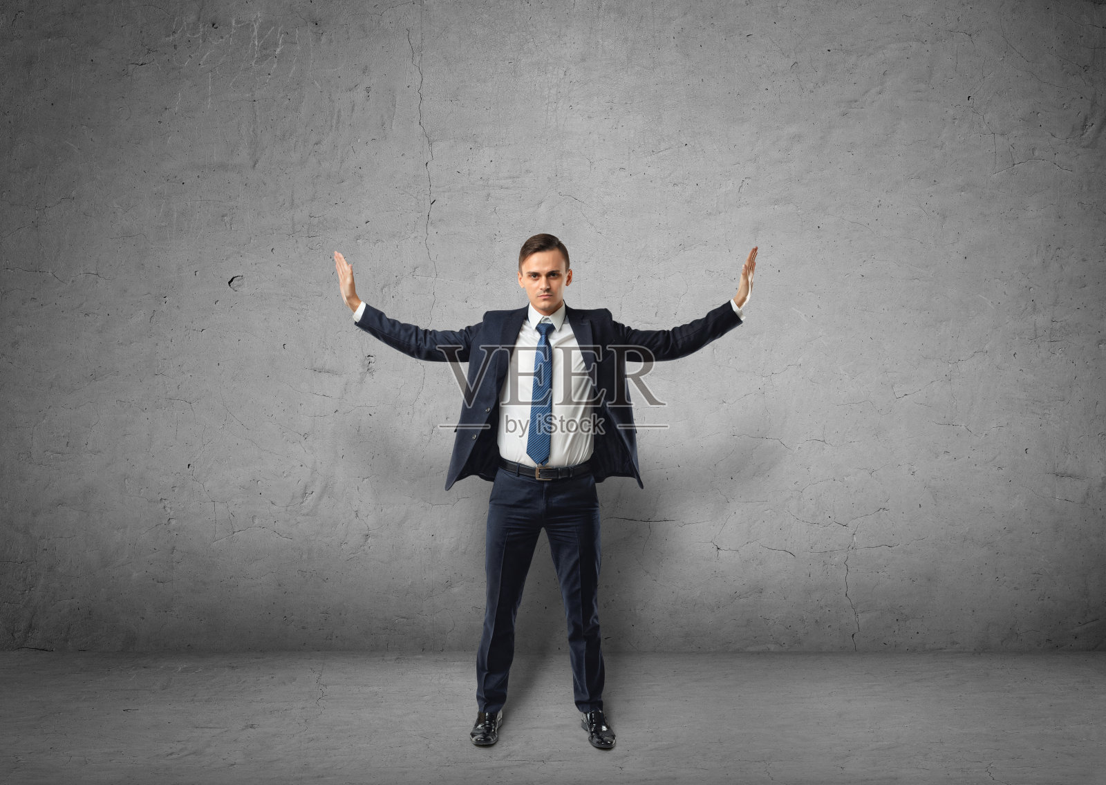 年轻的商人站在那里用手推着看不见的墙照片摄影图片