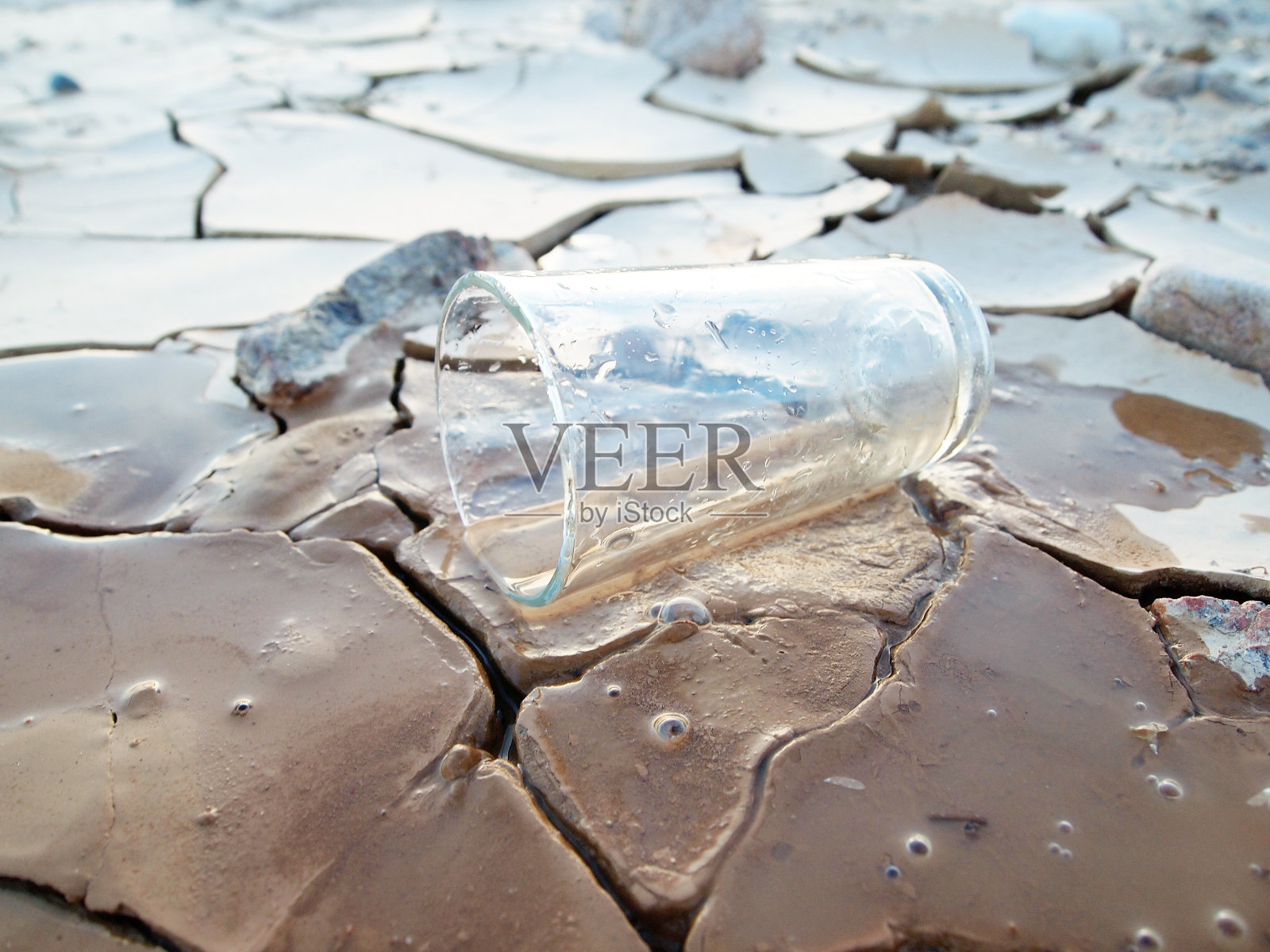 一杯水躺在破碎的土地上照片摄影图片