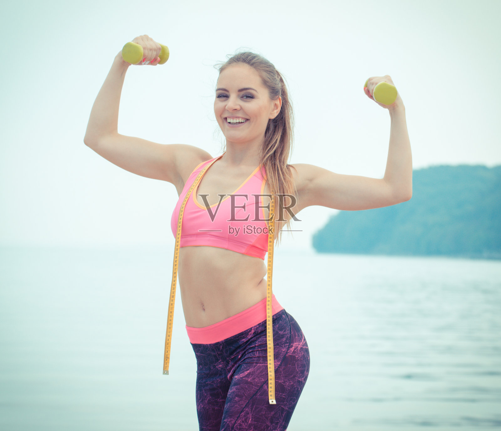 苗条的女孩穿着运动服，用哑铃做厘米运动照片摄影图片