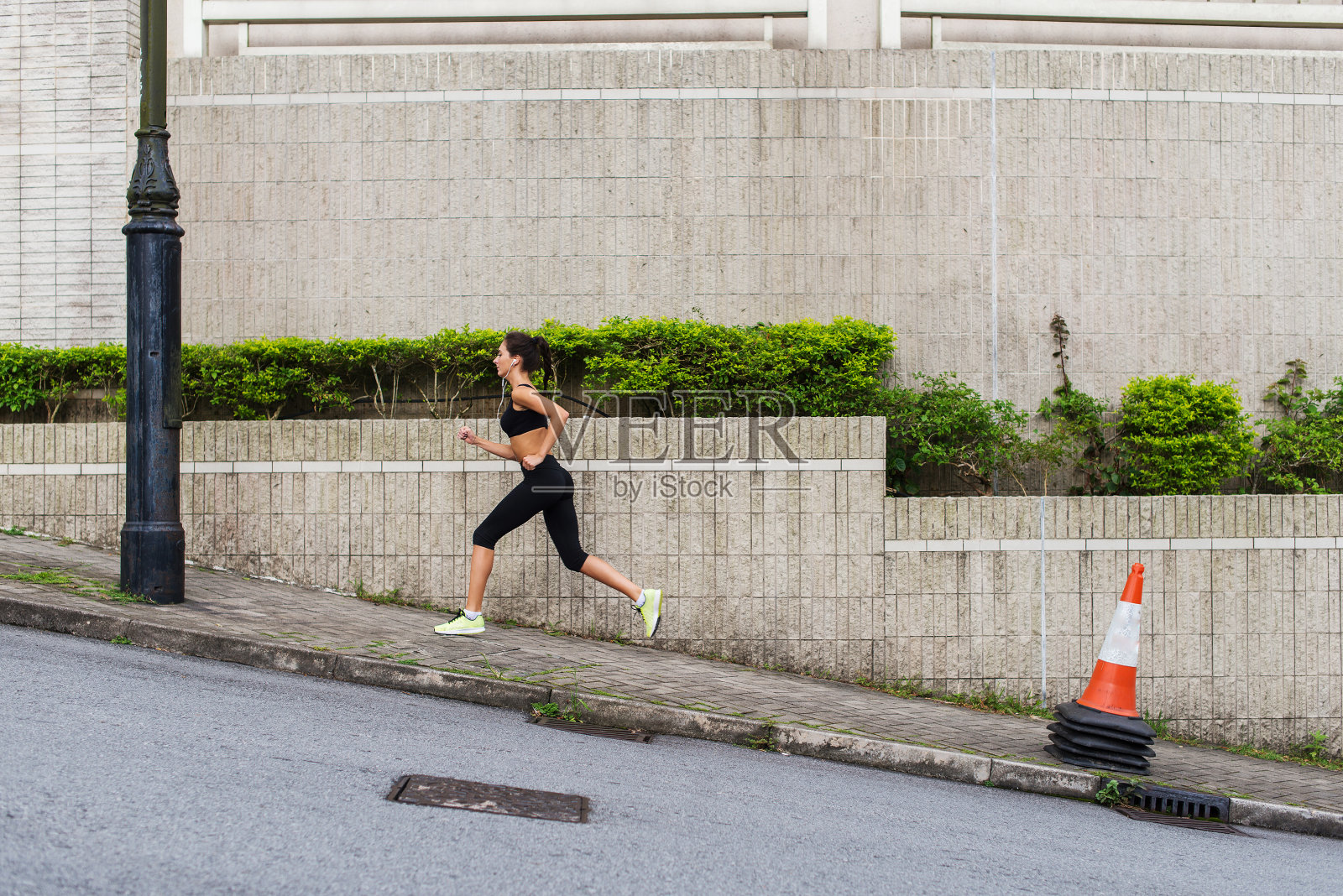 苗条的年轻女子在城市街道的人行道上跑上坡照片摄影图片