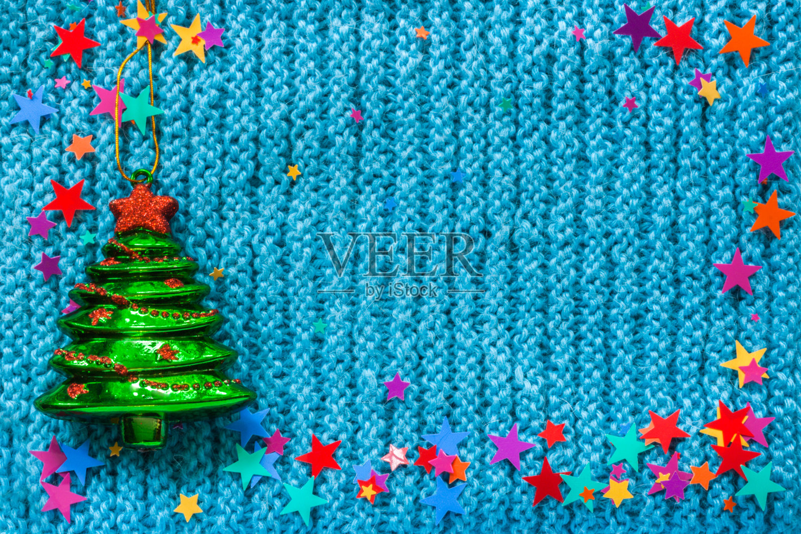 玻璃玩具圣诞树和星星在蓝色编织的背景。照片摄影图片