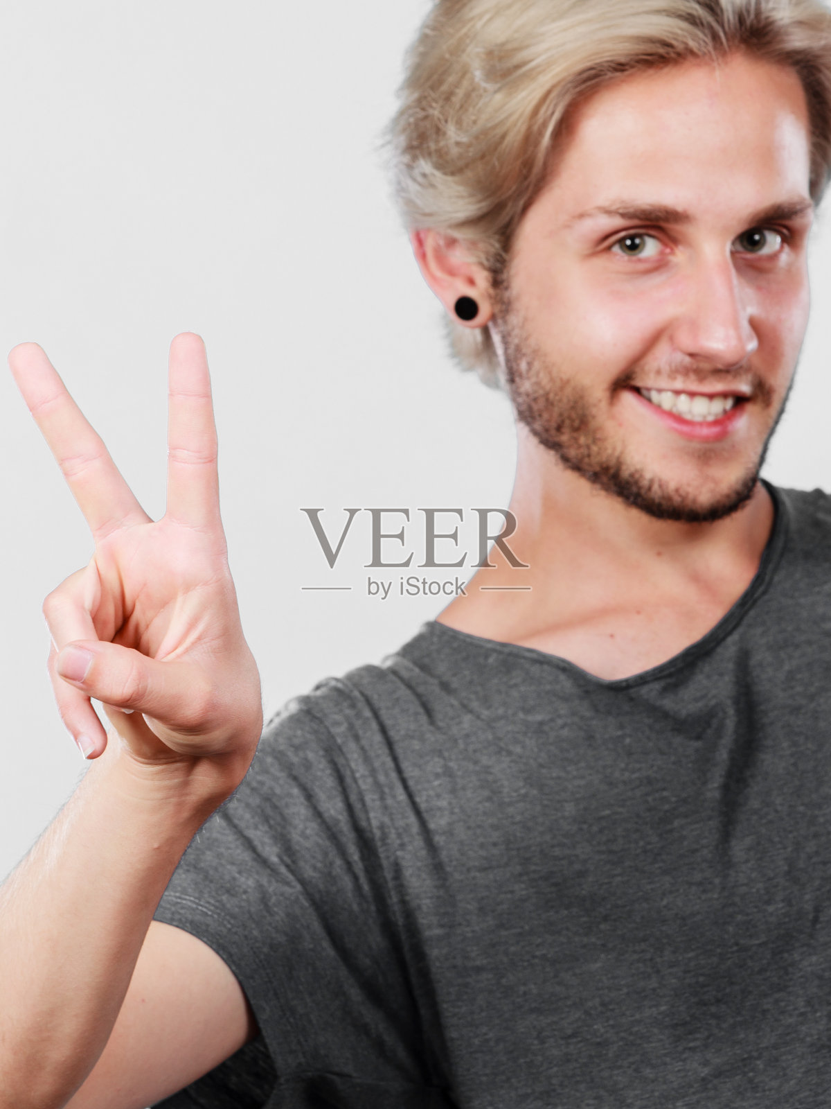 心满意足的年轻人展示着胜利的迹象照片摄影图片