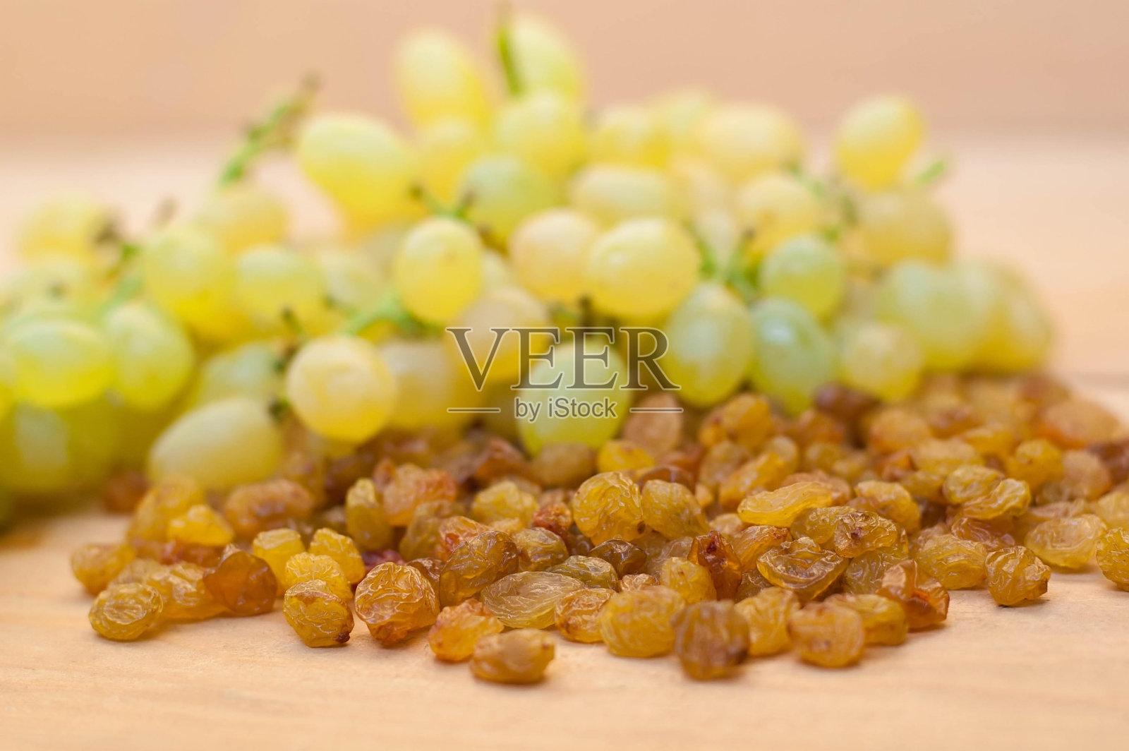 木桌上放着葡萄干和新鲜葡萄。照片摄影图片