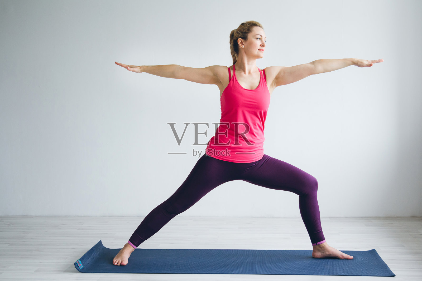 一个年轻女人在白色的房间里做瑜伽练习。照片摄影图片