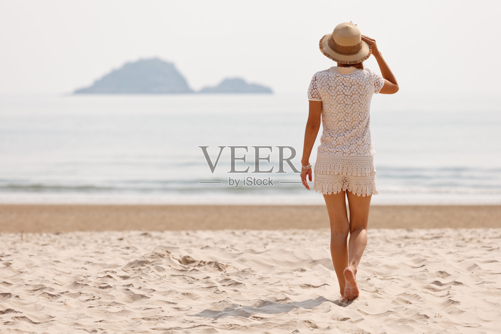 海滩上戴着帽子的女人照片摄影图片