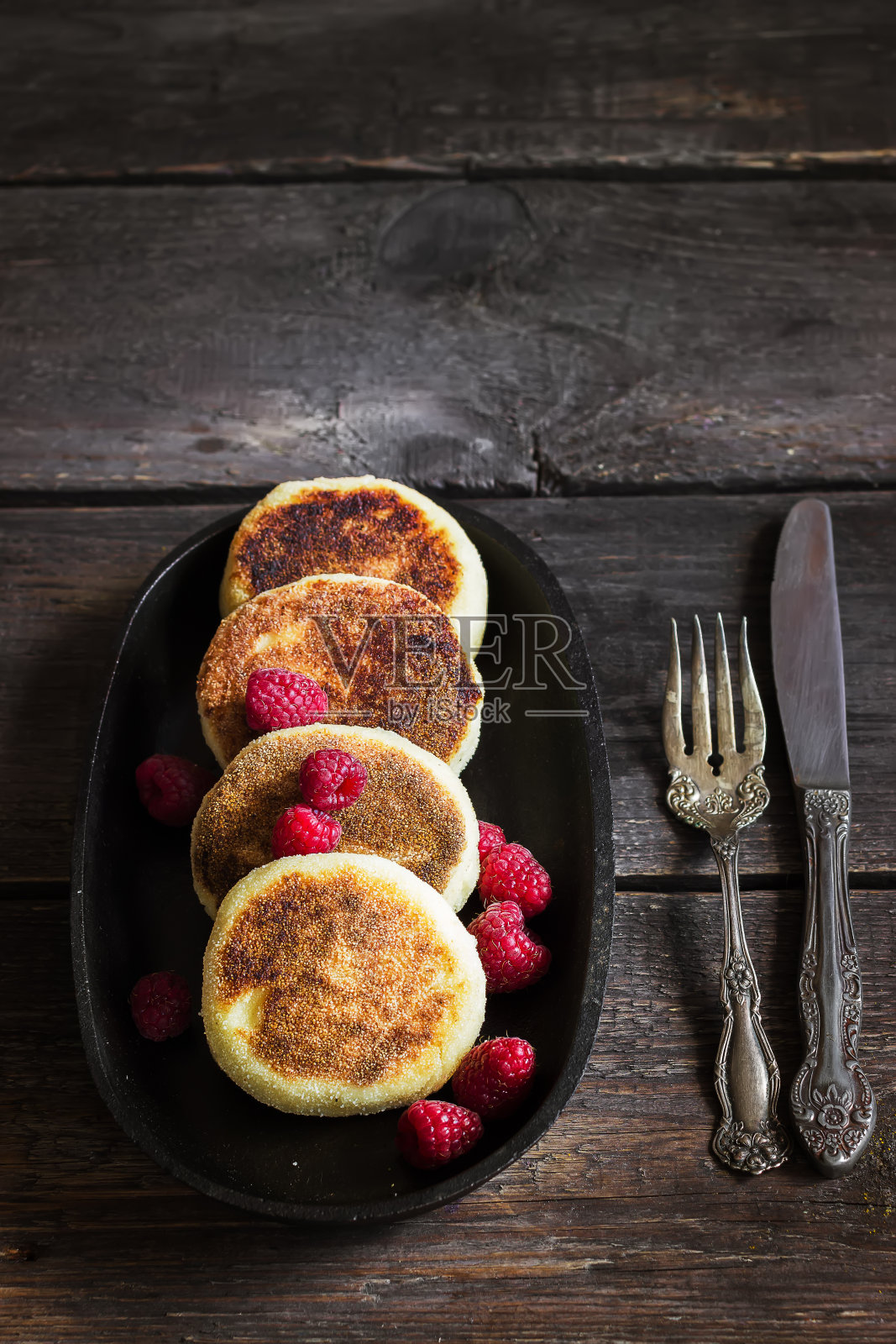 旧铁锅上放着野莓白干酪煎饼。照片摄影图片
