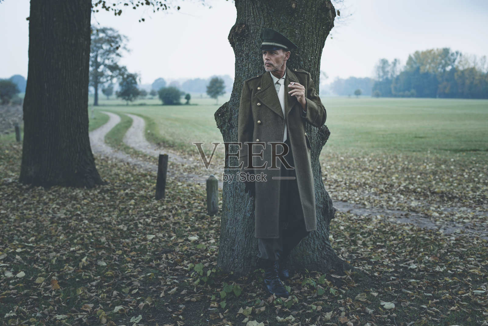 坐在树下抽烟的复古1940年代军官。照片摄影图片