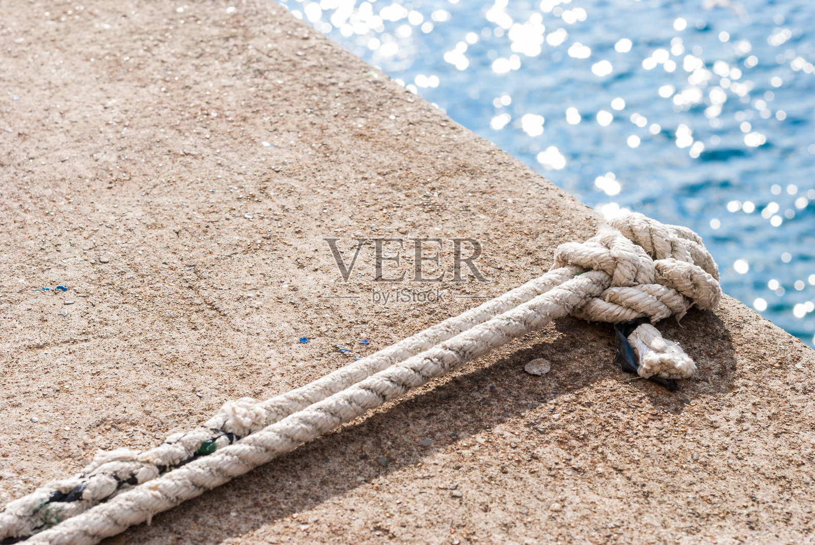 以蓝色的大海为背景，在码头上打结照片摄影图片