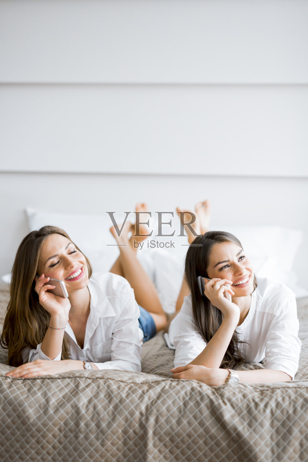 两个女孩躺在床上谈笑风生照片摄影图片