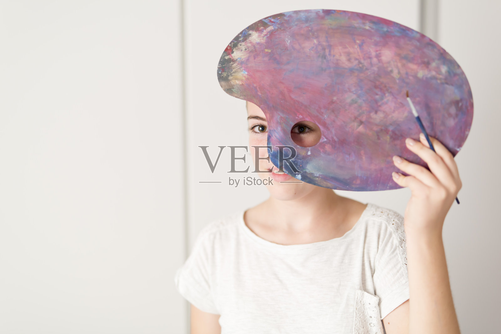 少年用它调色板上的颜料来涂油。照片摄影图片