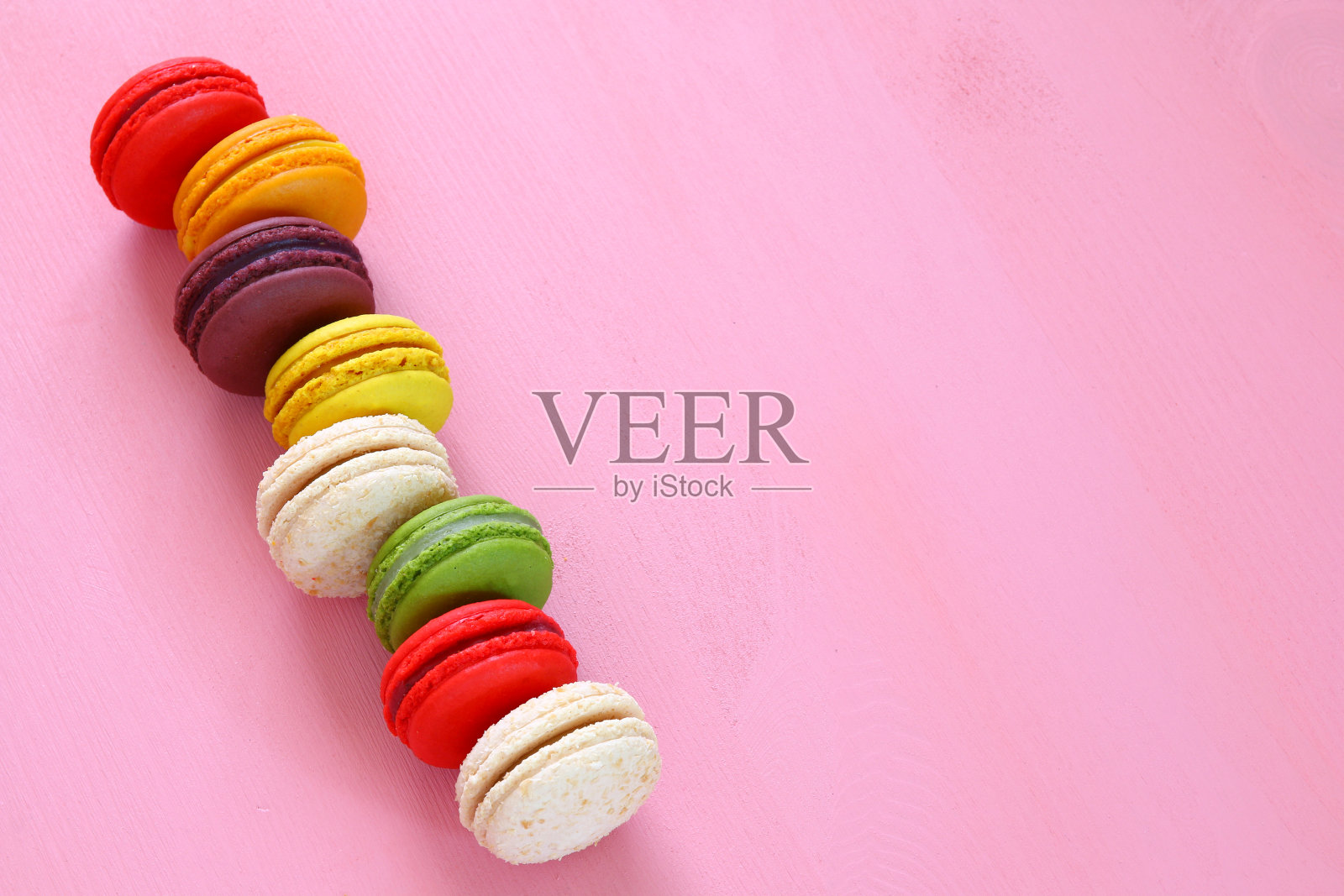 粉红色背景上的彩色马卡龙。照片摄影图片