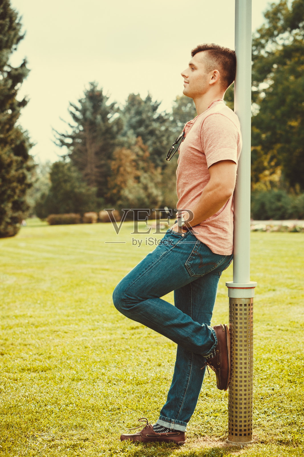 放松的男孩靠在杆子上。照片摄影图片