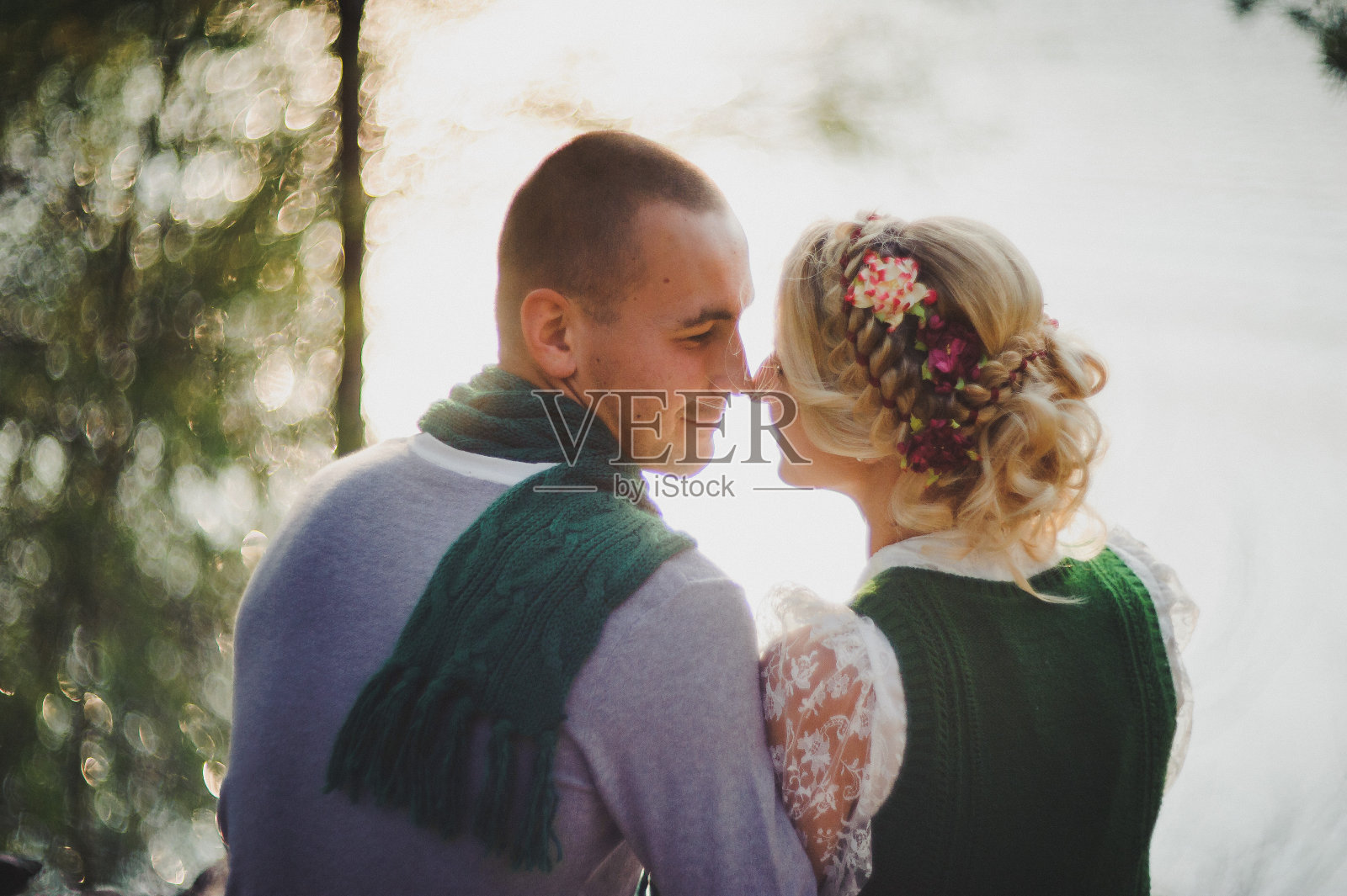 浪漫的情侣坐在树根上夕阳的背景下照片摄影图片