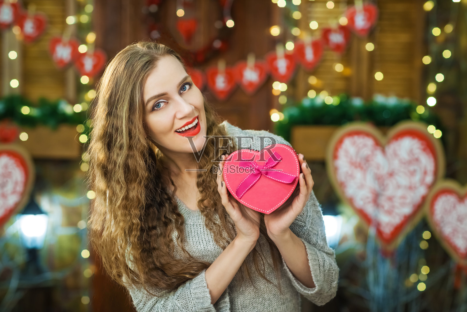 美丽的金发抱着盒子在心脏的形式照片摄影图片