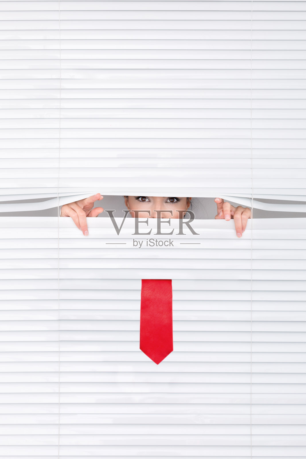 一个女人透过百叶窗往外看的肖像。照片摄影图片