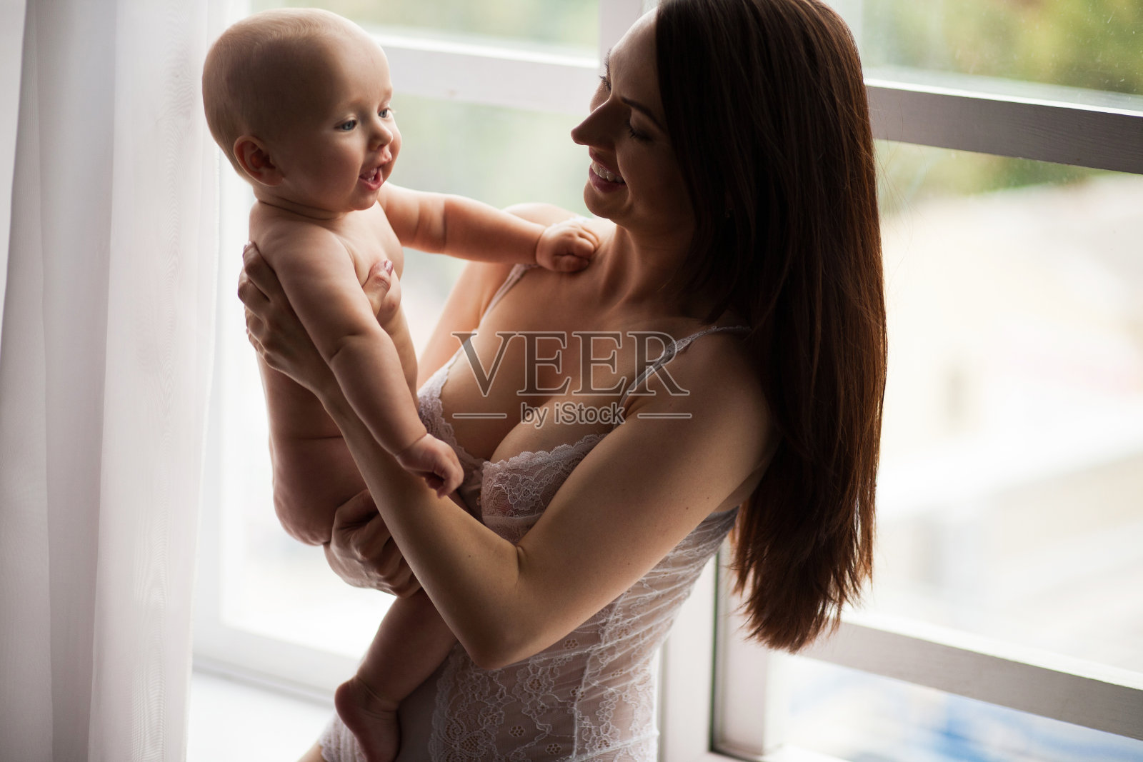 年轻的母亲和她的孩子玩。照片摄影图片