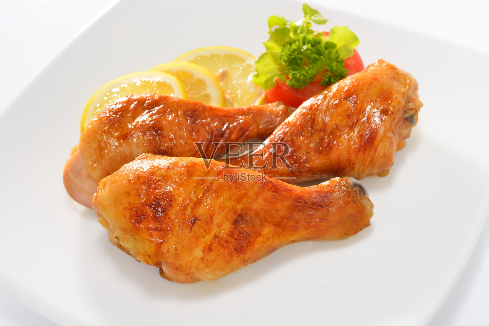 一盘三根加柠檬片的烤鸡腿照片摄影图片