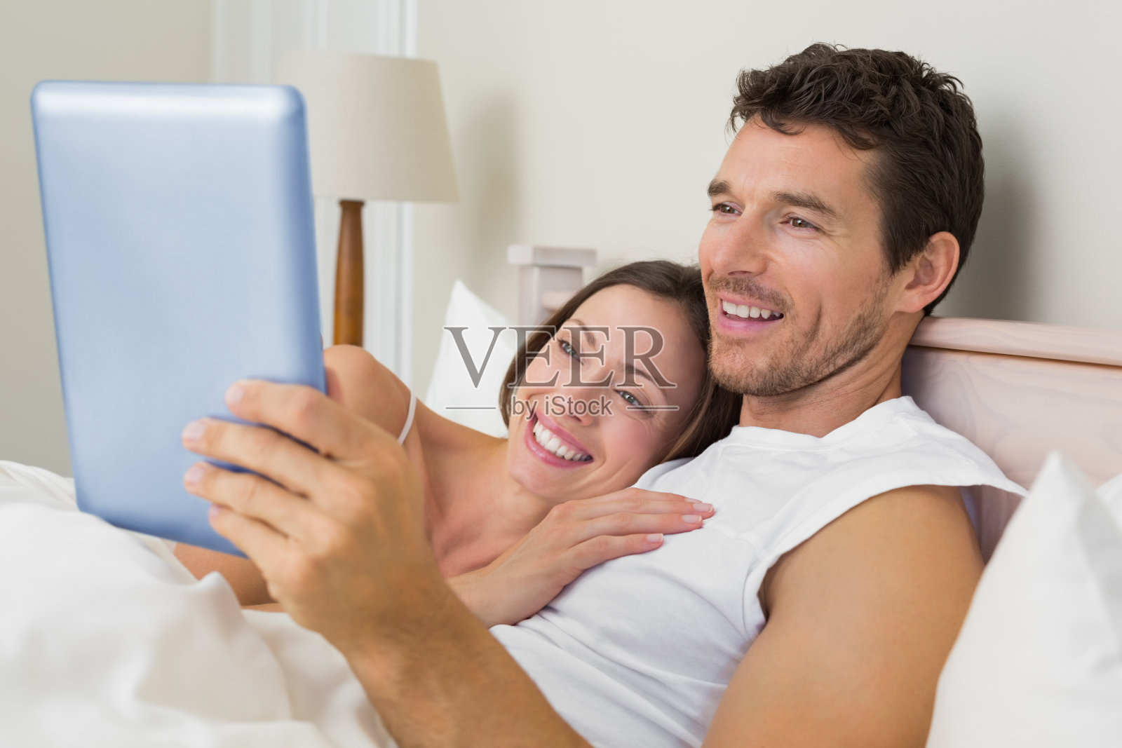 夫妇在床上使用电子平板电脑照片摄影图片