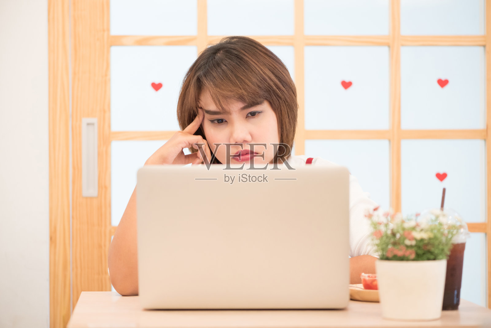 泰国女孩思考一个问题，以一个心脏与窗口的背景。工作的概念。照片摄影图片