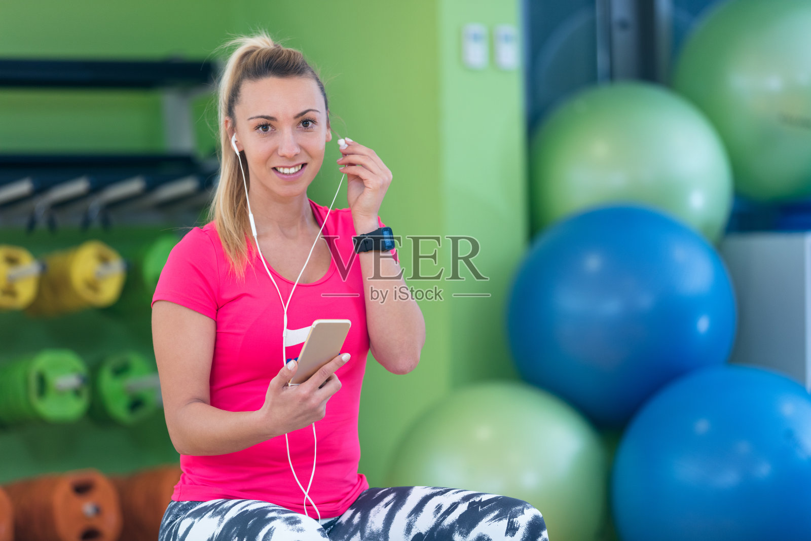 年轻漂亮的女人在健身房用智能手机照片摄影图片
