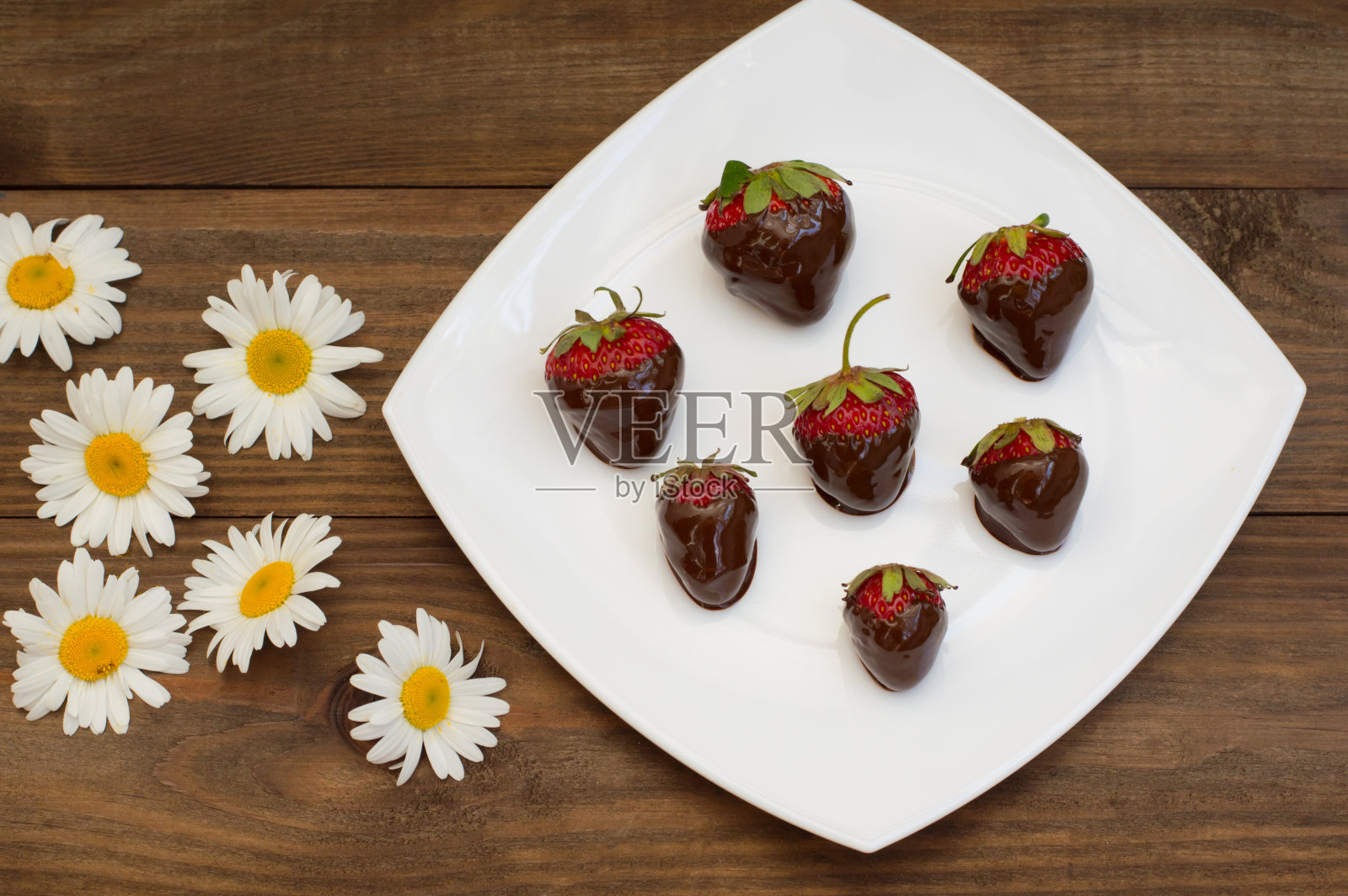 在一个白色的方形盘子里蘸着巧克力的草莓。木照片摄影图片