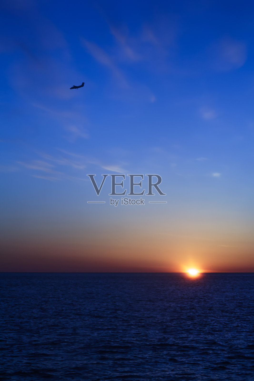 日落天空背景上飞机的剪影。照片摄影图片