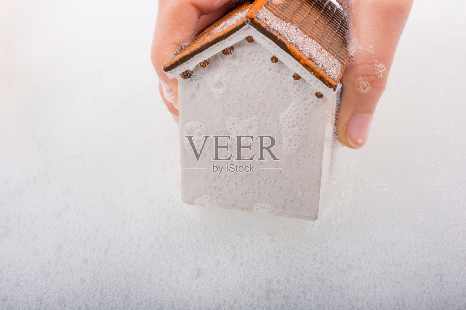 手持泡沫水中的模型房屋照片摄影图片