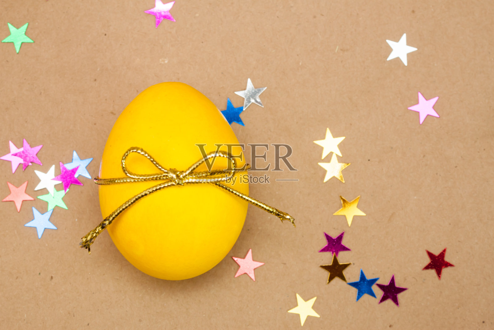 牛皮纸背景上有蝴蝶结的黄色鸡蛋照片摄影图片