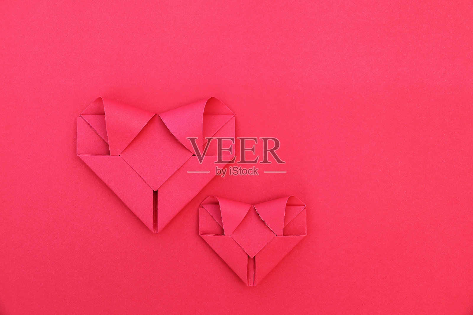 两颗在红色纸上折叠的心形图案照片摄影图片