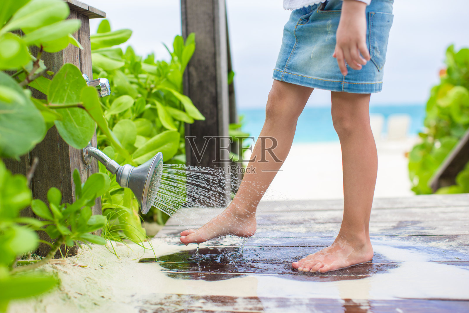 一个女孩在海滩上洗掉了脚上的沙子照片摄影图片
