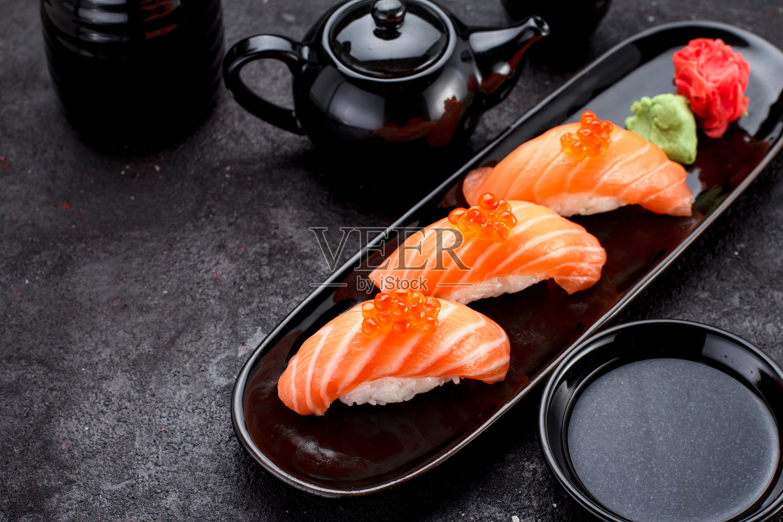 黑色盘子上的三文鱼寿司和深色的混凝土背景。照片摄影图片