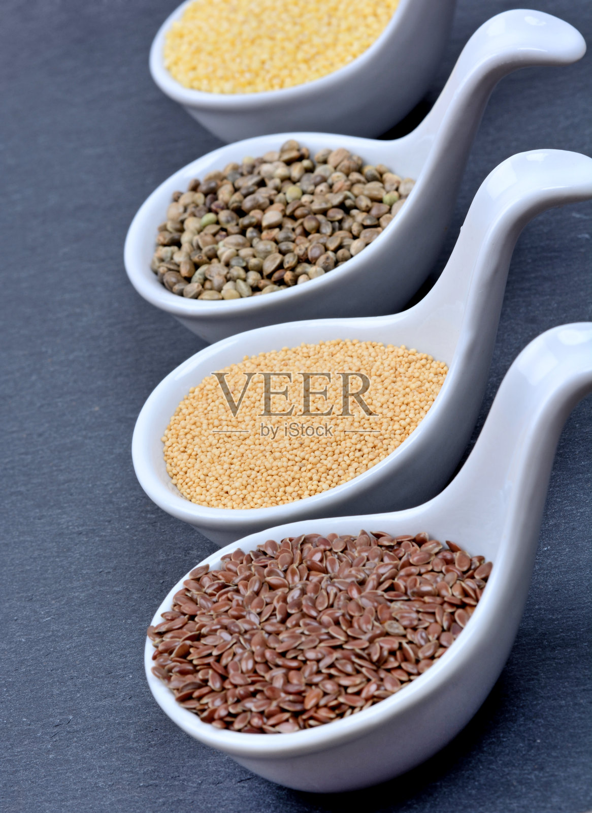 陶瓷勺里放着不同的种子照片摄影图片