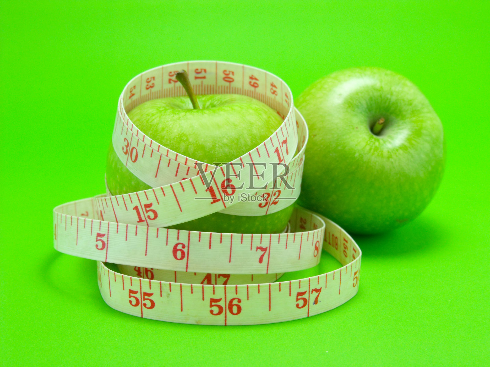 用卷尺裹住一个青苹果作为饮食照片摄影图片