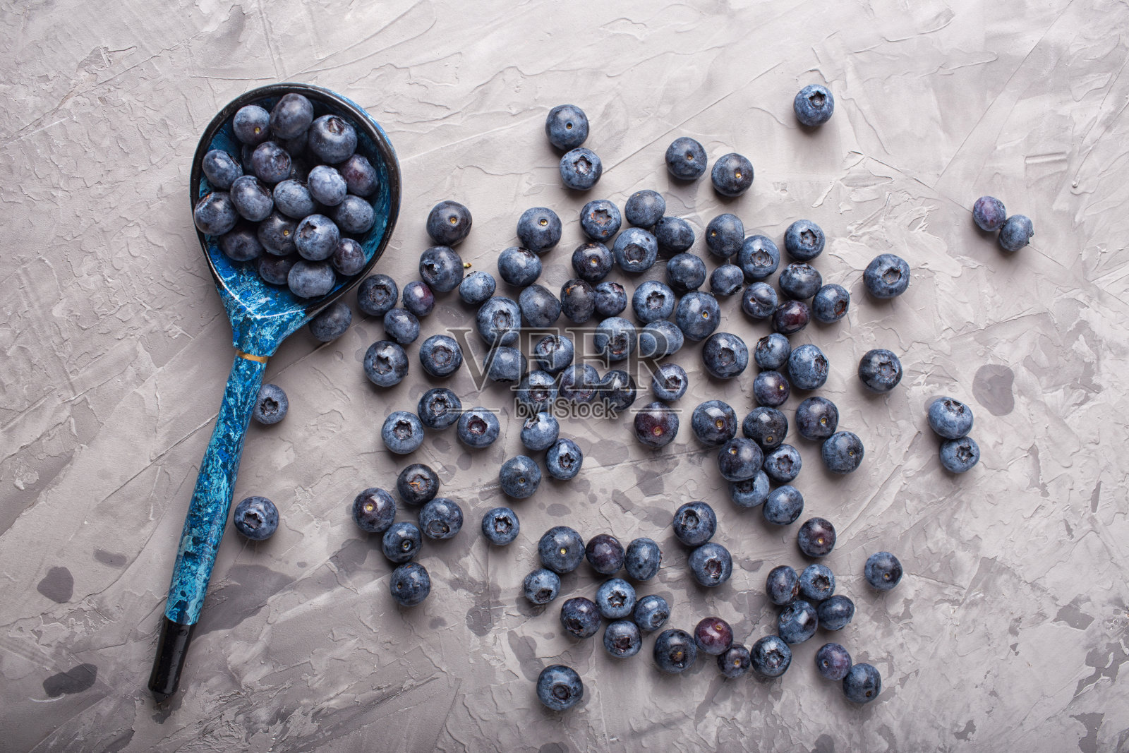 混凝土背景上的花园蓝莓和老式木勺。俯视图照片摄影图片
