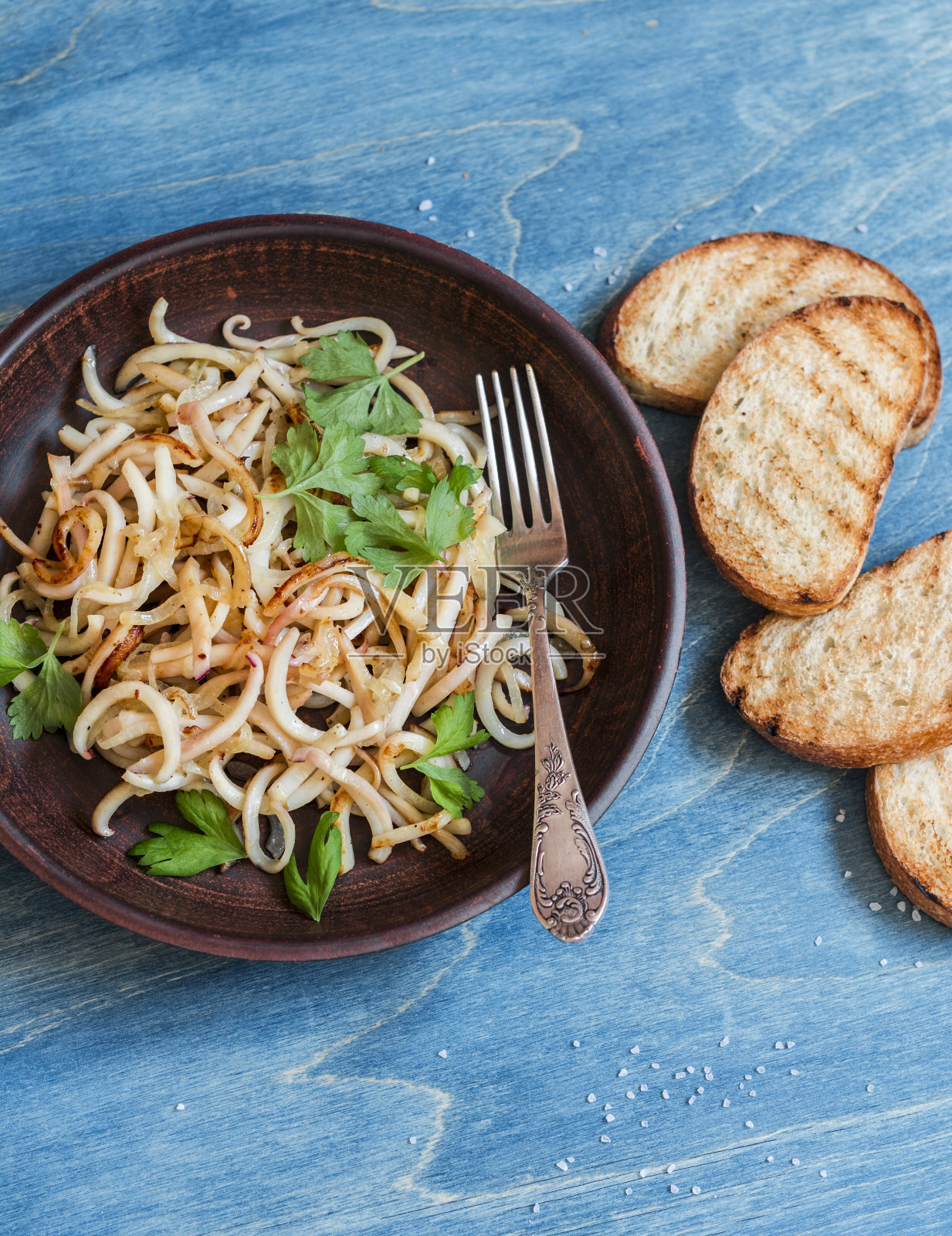 木桌上放着炸鱿鱼和烤面包。照片摄影图片