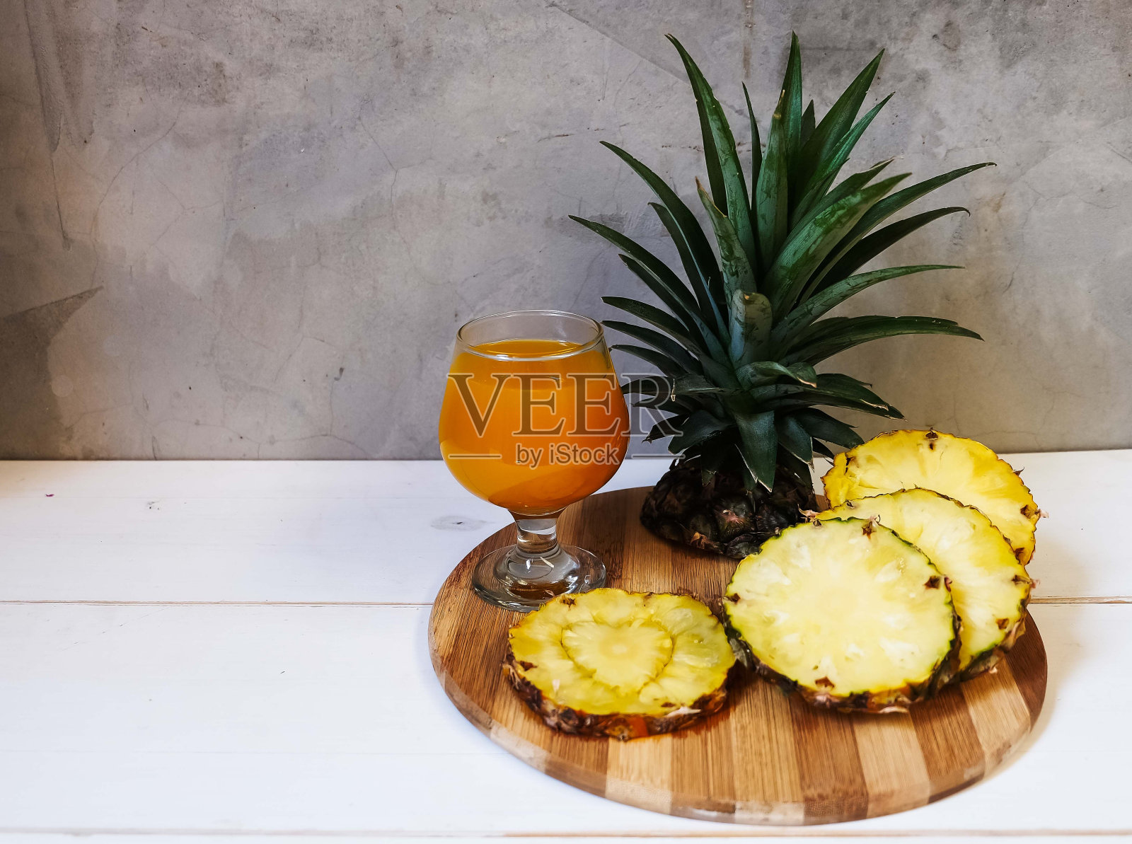 菠萝汁和菠萝滑片放在木盘上，放在白色的桌子上照片摄影图片