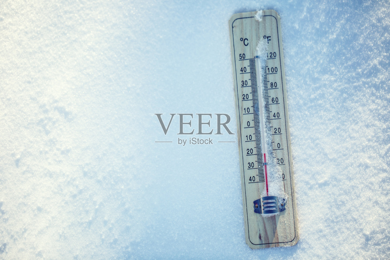 雪上的温度计显示零度以下的低温。照片摄影图片